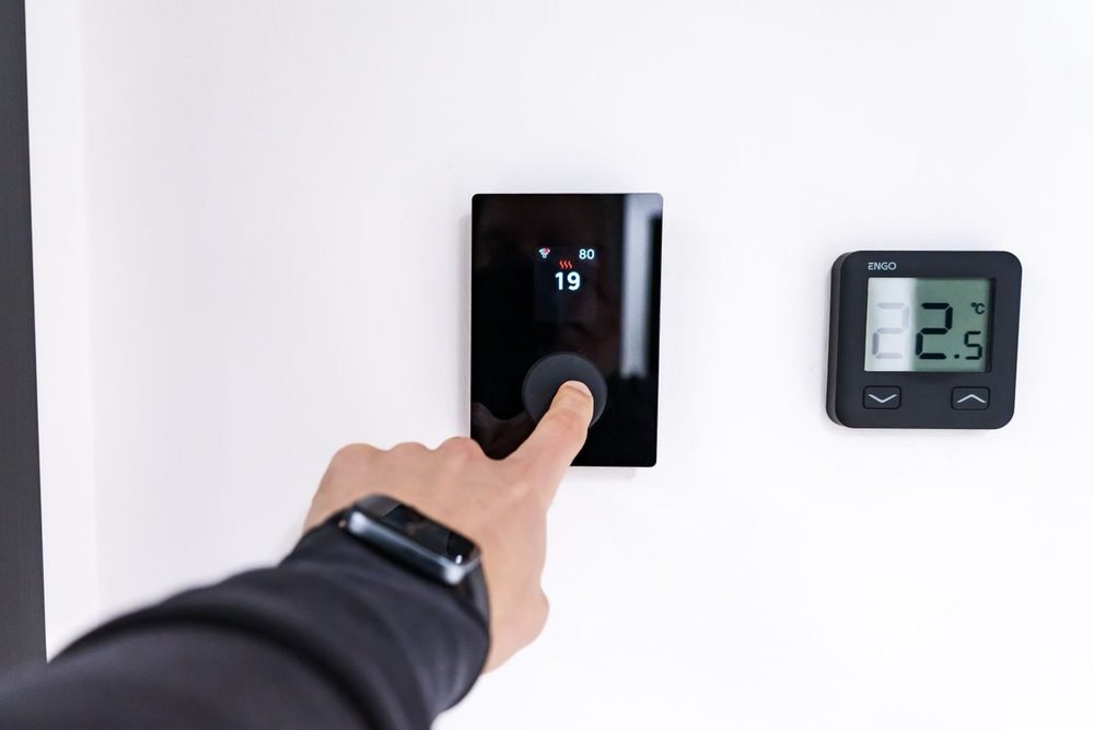 Mano ajustando un termostato inteligente para ahorrar energia en casa